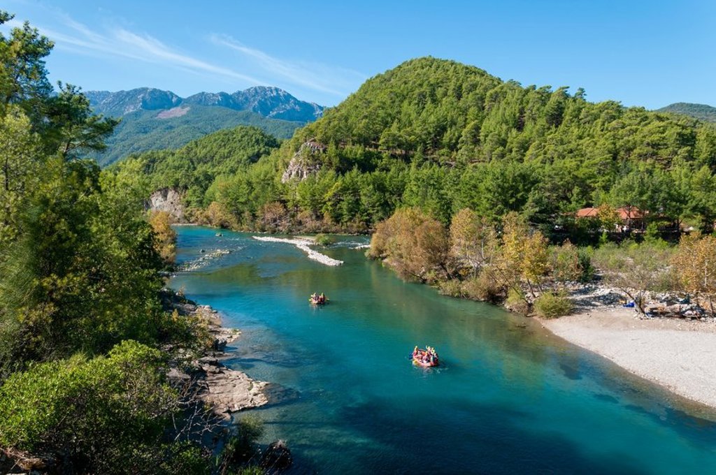 Turquoise kust in Turkije met groene bomen en bergen op de achtergrond, passend bij een familiereis Turkije.