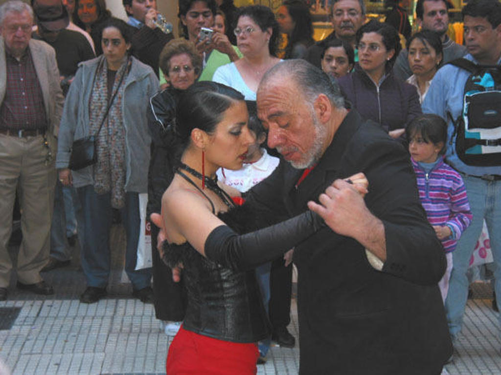 Tango-dansers op straat in Argentinië, omringd door toeschouwers.