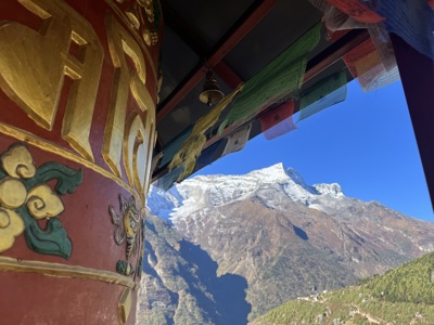 Gebedsmolen met kleurrijke vlaggen langs de Route Nepal Everest Base Camp, met besneeuwde Himalaya op de achtergrond.