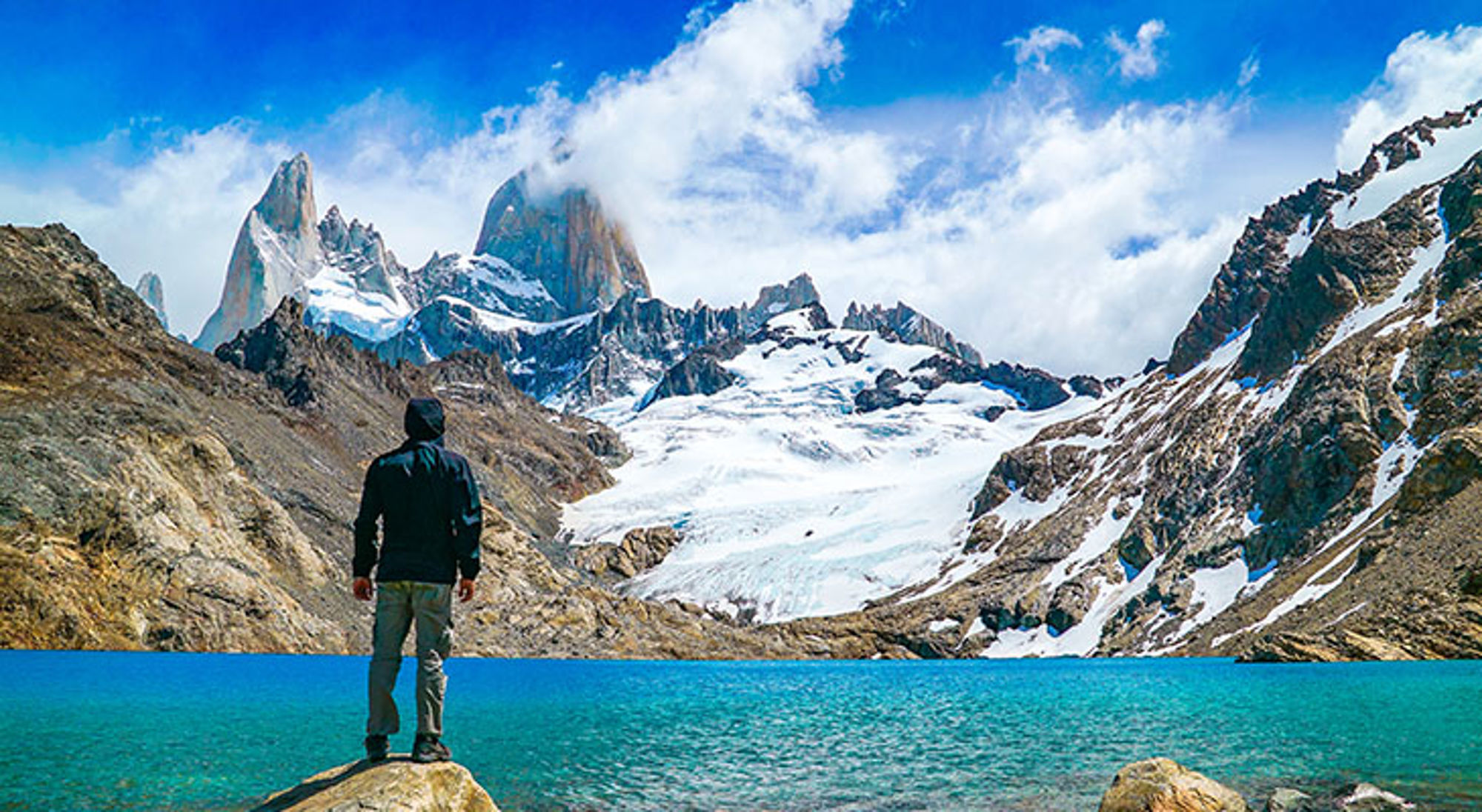 Man kijkt uit op besneeuwde bergtoppen in de buurt van El Calafate Wandelaar bij turquoise bergmeer met gletsjer en granieten pieken in Patagonië.