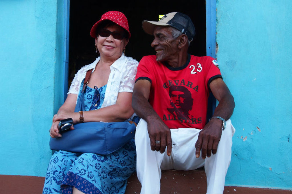 Cubaans stel zit in een deuropening van een blauw huis, tijdens familiereis Cuba Hoogtepunten.