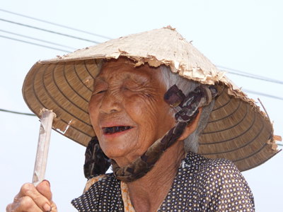 Oudere Vietnamese vrouw met traditionele conische hoed, tijdens Route Vietnam.