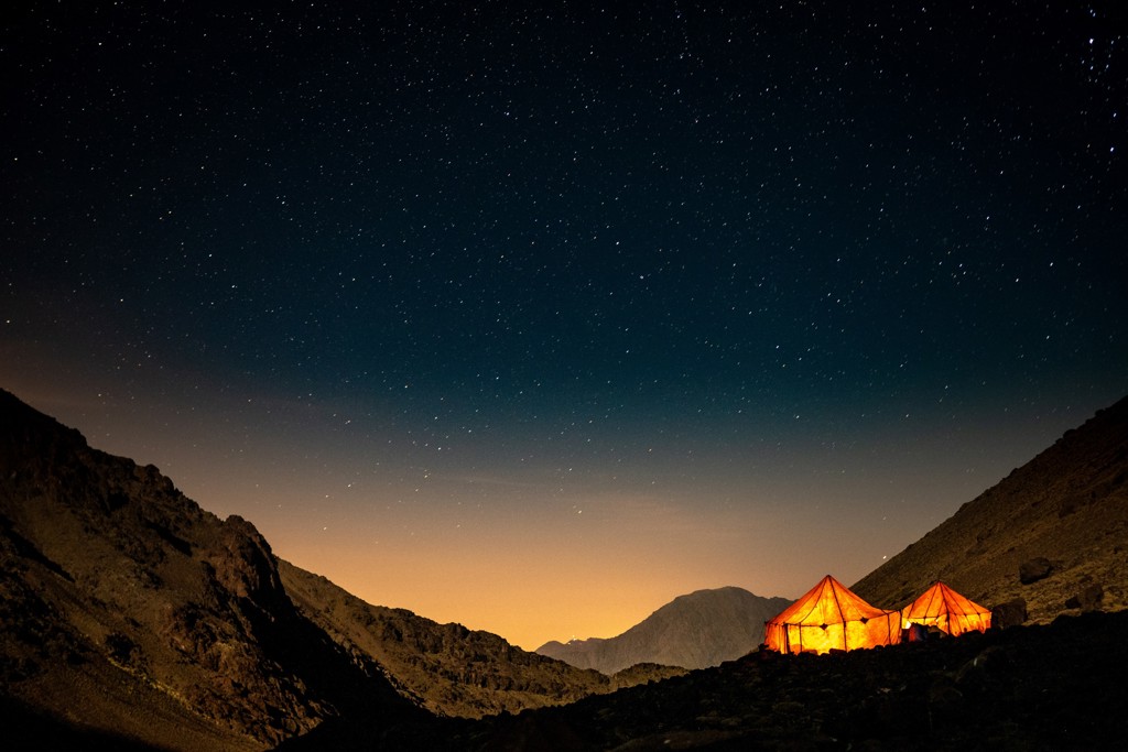 Verlichte tenten onder een sterrenhemel tijdens de beklimming van Mount Toubkal in Marokko.