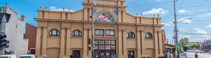 Gevel van Queen Victoria Market in Melbourne, met tramkabels en voorbijgangers op straat.