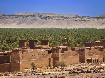 Kasbah bij een palmoase in de Draa-vallei, met bergen op de achtergrond in Marokko.