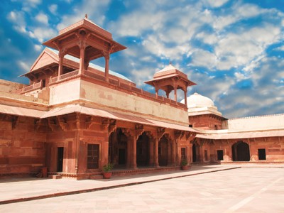 Binnenplaats van een roodstenen paleisfort in Rajasthan, met paviljoens en zuilengalerijen onder een blauwe lucht.