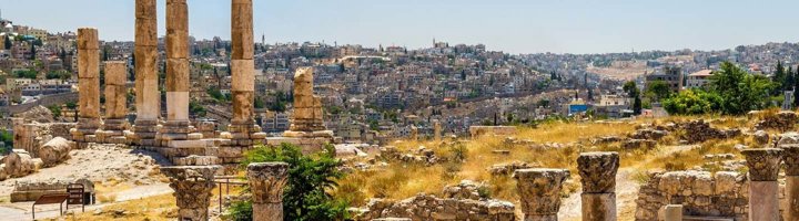 Skyline van Amman, Jordanië, met moderne gebouwen op heuvels bij zonsondergang.