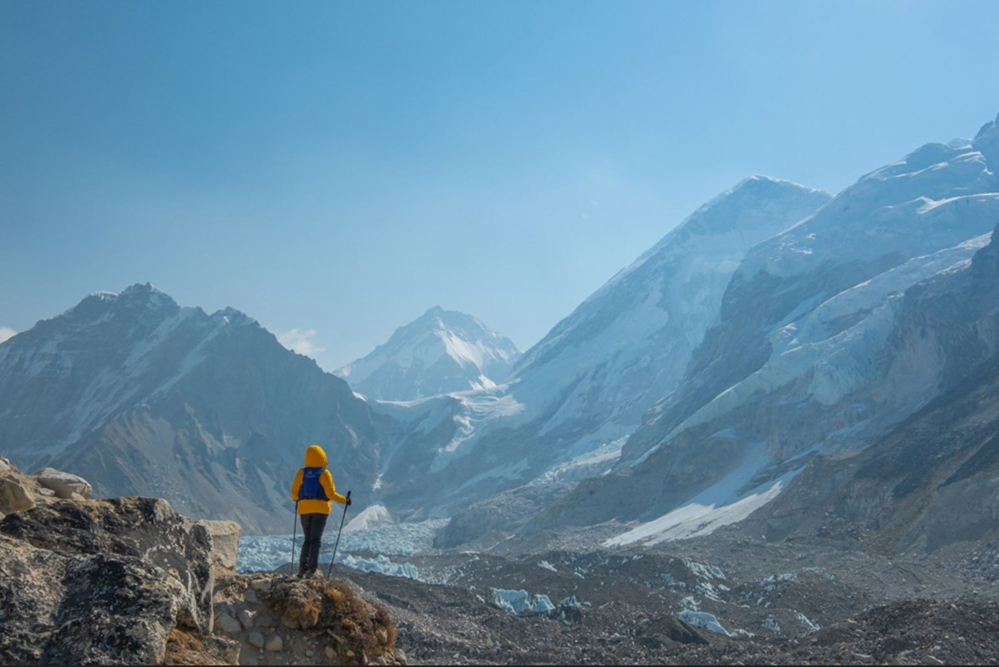 Wandelaar kijkt uit over een gletsjer en besneeuwde Himalaya-bergen in Nepal.