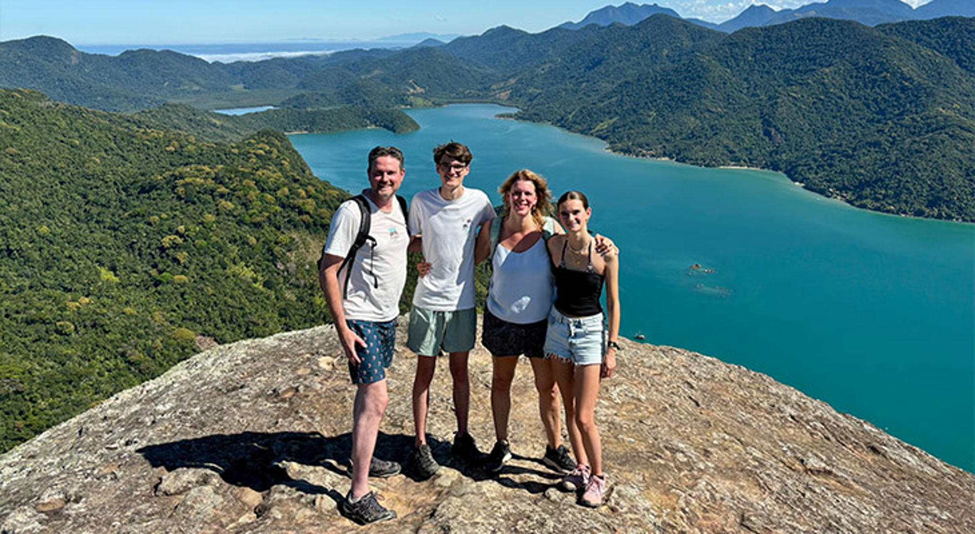 Familiereis Brazilië Gezin op uitzichtpunt boven een turquoise baai met groene bergen tijdens een wandeltocht.