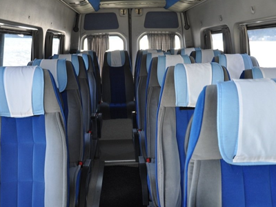 Interieur van een comfortabele minibus met blauwe stoelen voor vervoer tijdens een Balkanreis.