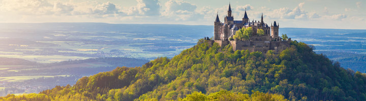 Kasteel Hohenzollern op een beboste heuvel in Duitsland, uitkijkend over het landschap.