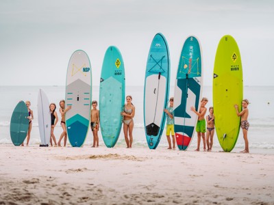 Kinderen op het strand met surf- en SUP-boards tijdens de Route Thailand Noord en Zuid.
