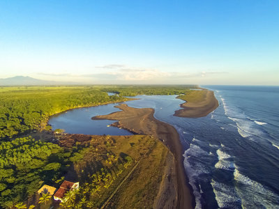 de Pacifische kust van Guatemala met zwarte zandstrand, riviermonding en mangrovebossen.