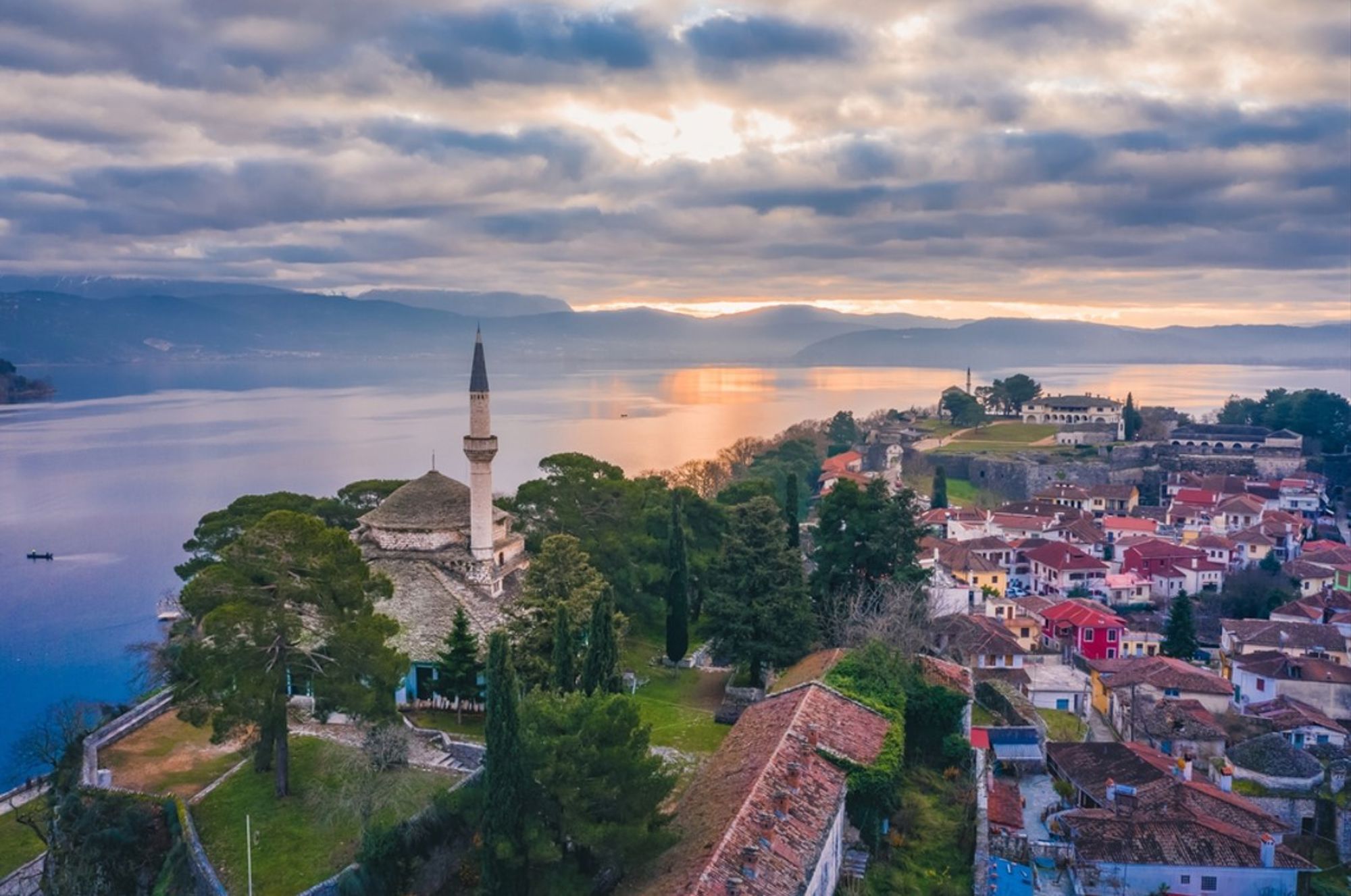 Uitzicht op Ioannina aan het Pamvotismeer met de Fethiye-moskee en het kasteel bij zonsondergang.