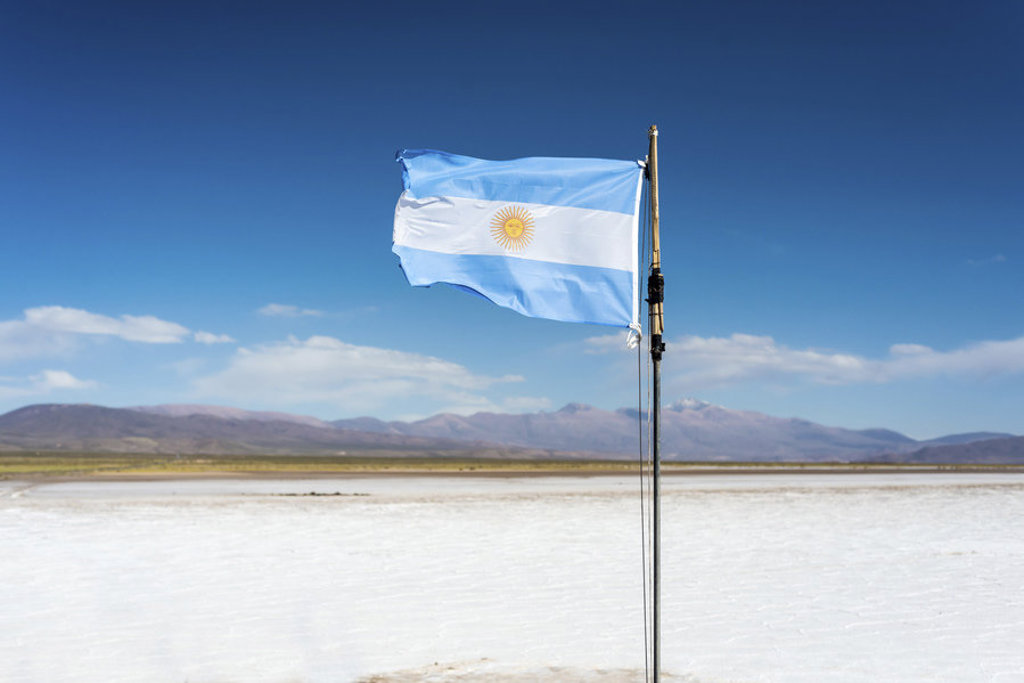 Argentijnse vlag wappert boven een zoutvlakte met bergen op de achtergrond tijdens een groepsrondreis Argentinië.