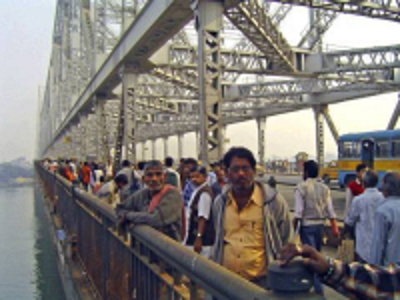 Drukke stalen brug in Orissa met voetgangers en een bus langs de rivier.