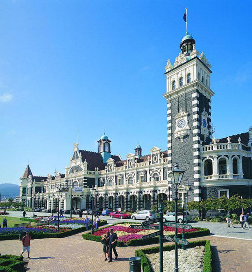 Historisch treinstation van Dunedin met klokkentoren en bloemperken, Nieuw-Zeeland.