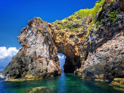 Rotsboog aan de kust van Thailand met helderblauw water en groene begroeiing, Route Thailand dag 14.