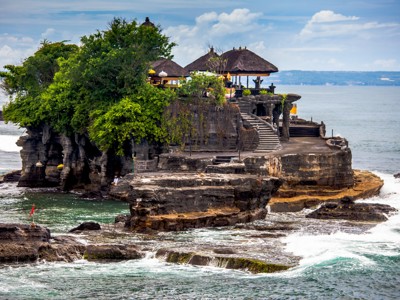 Tanah Lot-tempel op rots in zee bij Bali, met trappen en paviljoens tussen groen.