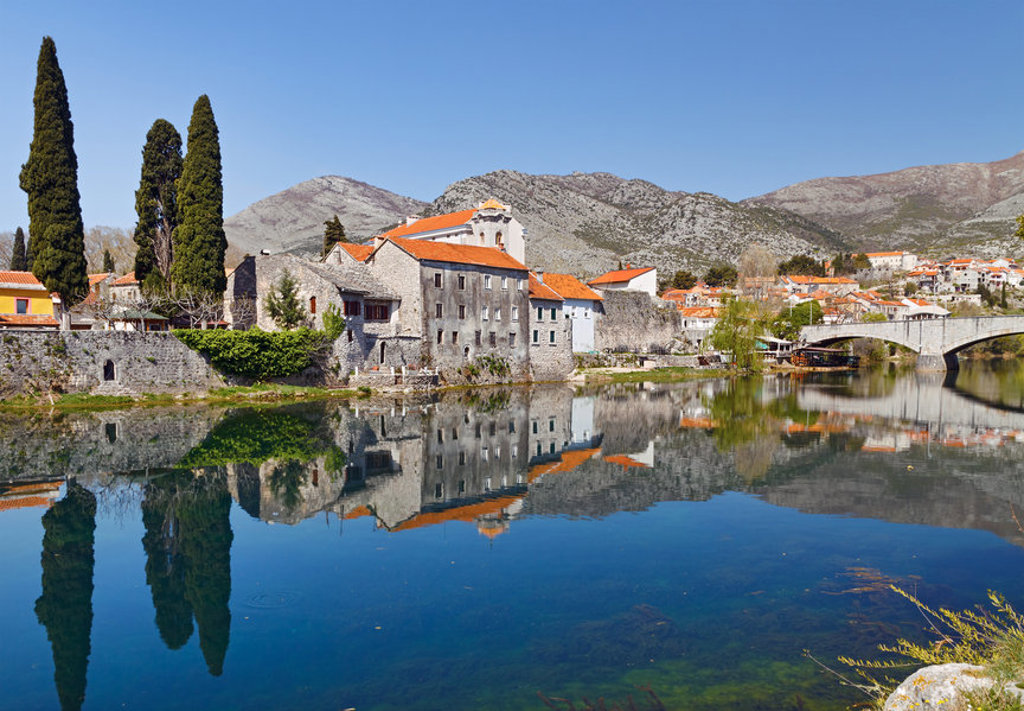 Historisch stadje aan de rivier met stenen huizen, brug en berglandschap op de Balkan.
