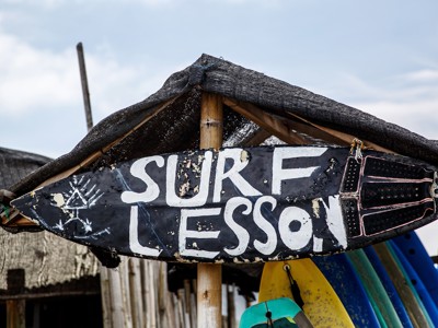 Surflesbord met tekst “Surf Lesson” bij een surfschool op Bali.