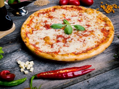 Pizza margherita met basilicum op een houten tafel, typisch Italiaans gerecht aan de Amalfikust.
