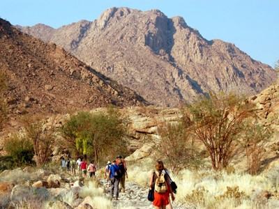 Wandelaars tijdens groepsrondreis Zuidelijk Afrika in rotsachtig berglandschap in Namibië.