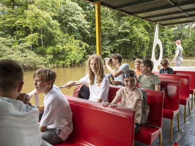 Boottocht over een rivier door het regenwoud in Costa Rica, met reizigers op rode banken.