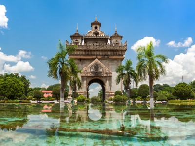 Patuxai-monument in Vientiane, Laos, met palmbomen en weerspiegeling in de vijver.