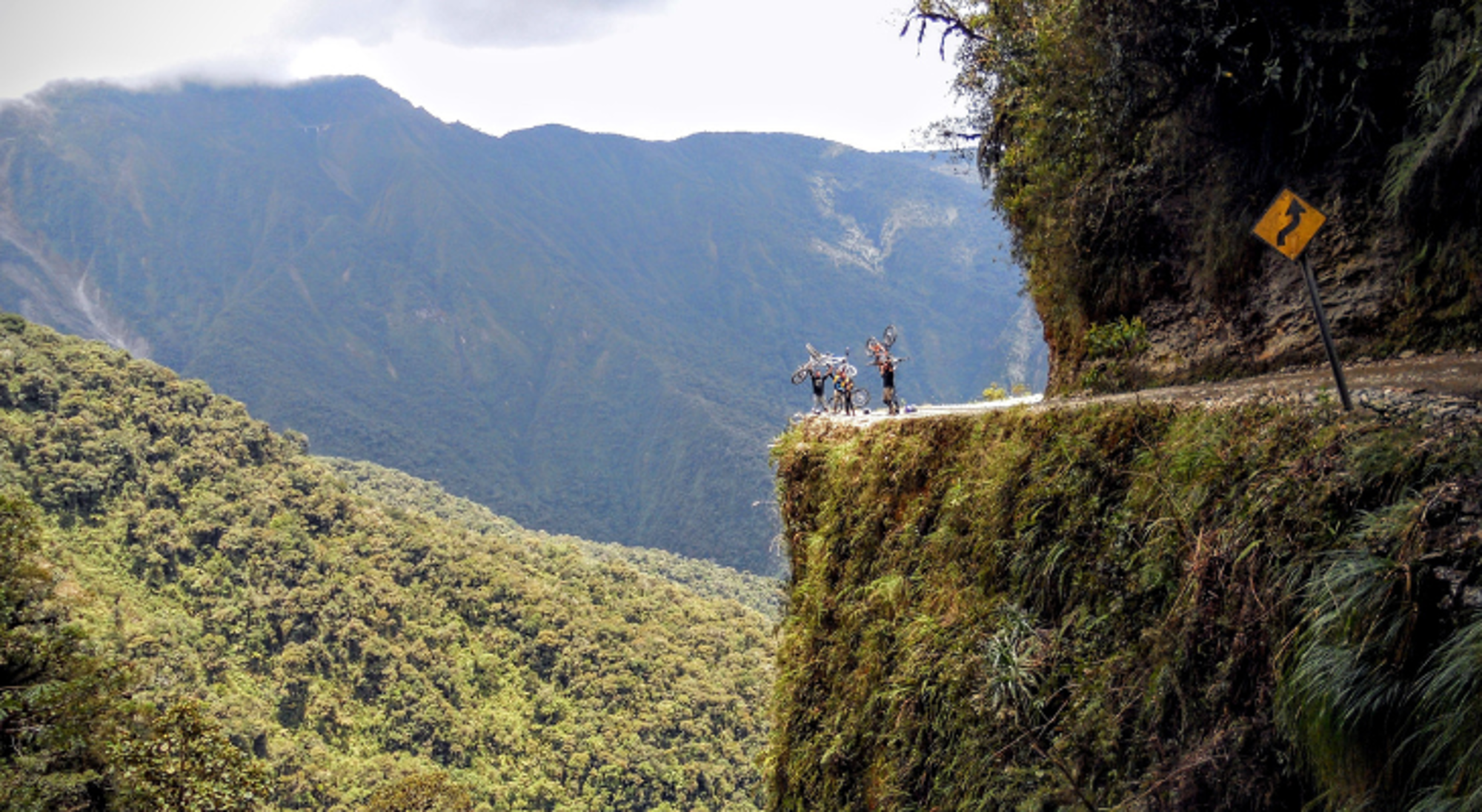 Death Road Fietsers met mountainbikes op de smalle Yungas Road langs een steile bergwand in Bolivia.