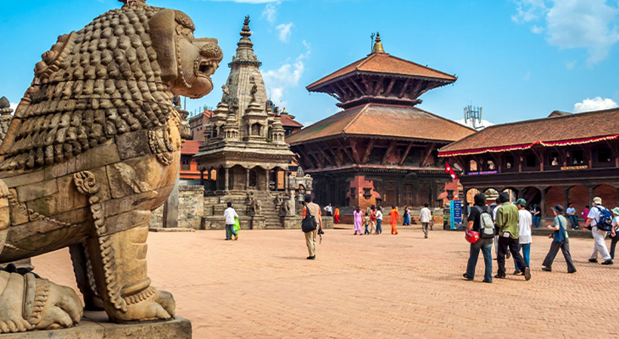 Patan Durbar Square in Kathmandu met stenen leeuwbeeld en tempels op het plein.