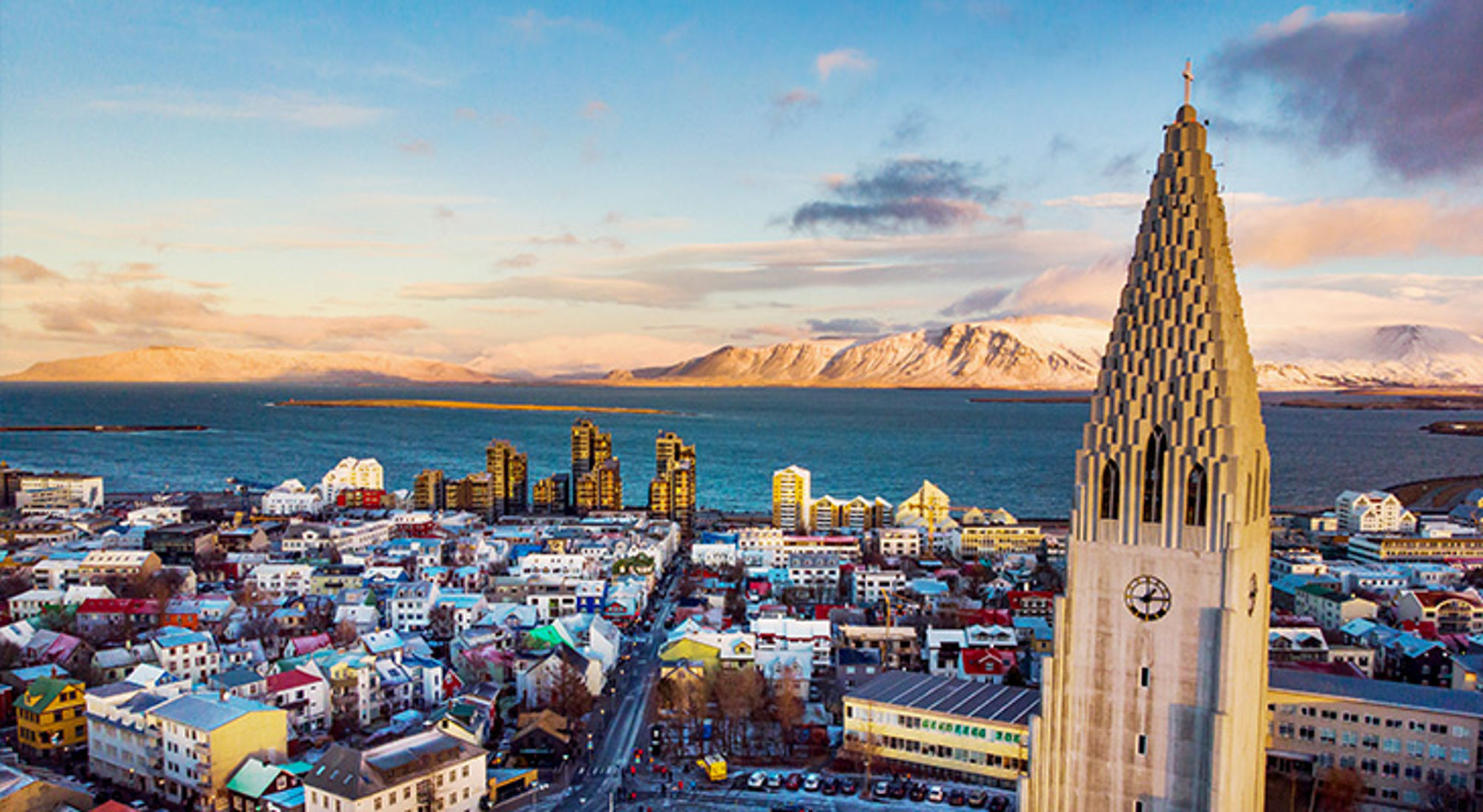 Uitzicht over Reykjavik Uitzicht over Reykjavik met de Hallgrímskirkja op de voorgrond en de baai en bergen bij zonsondergang.