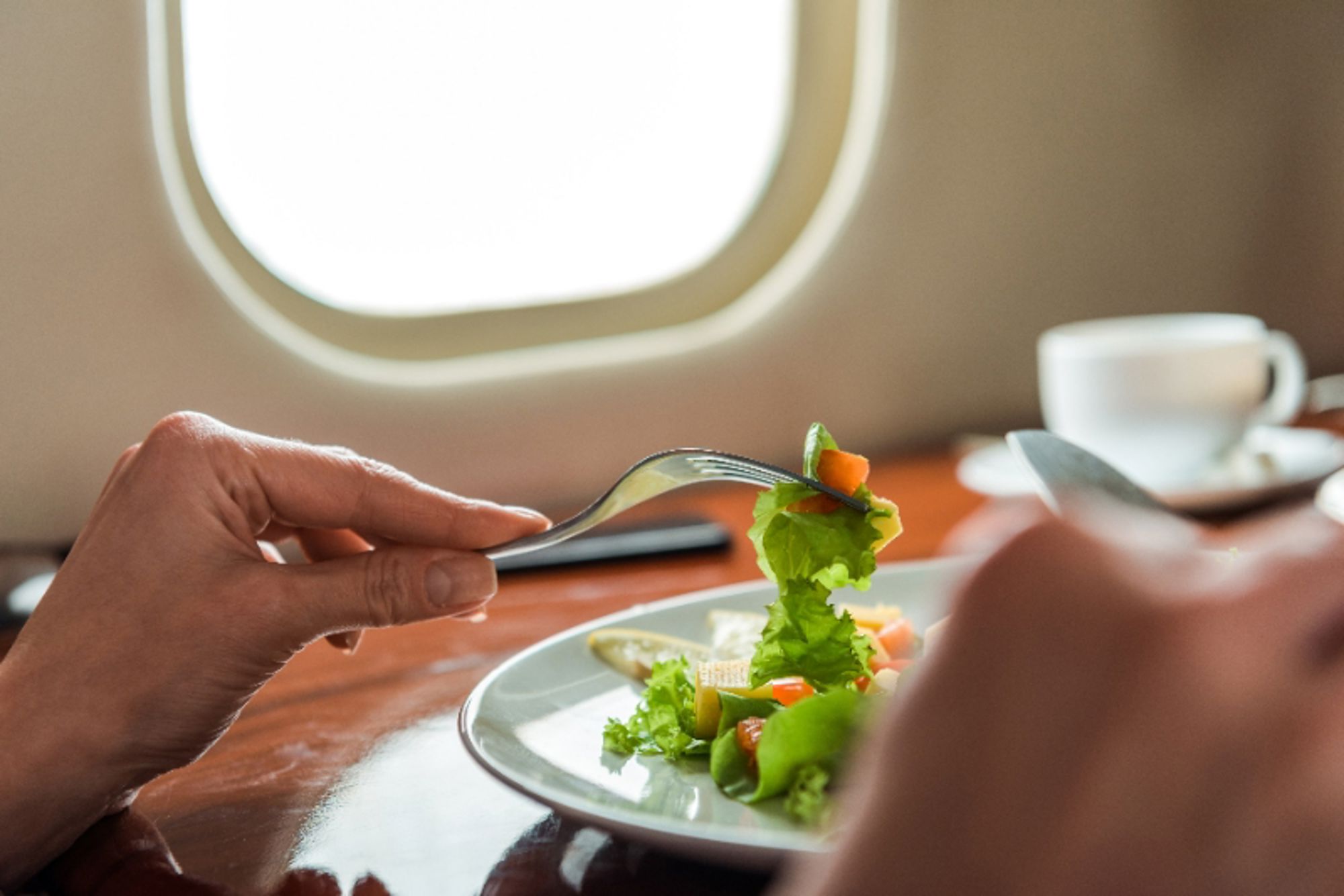 Eet een lichte maaltijd Passagier eet salade aan tafel bij het vliegtuigraam tijdens een vlucht.