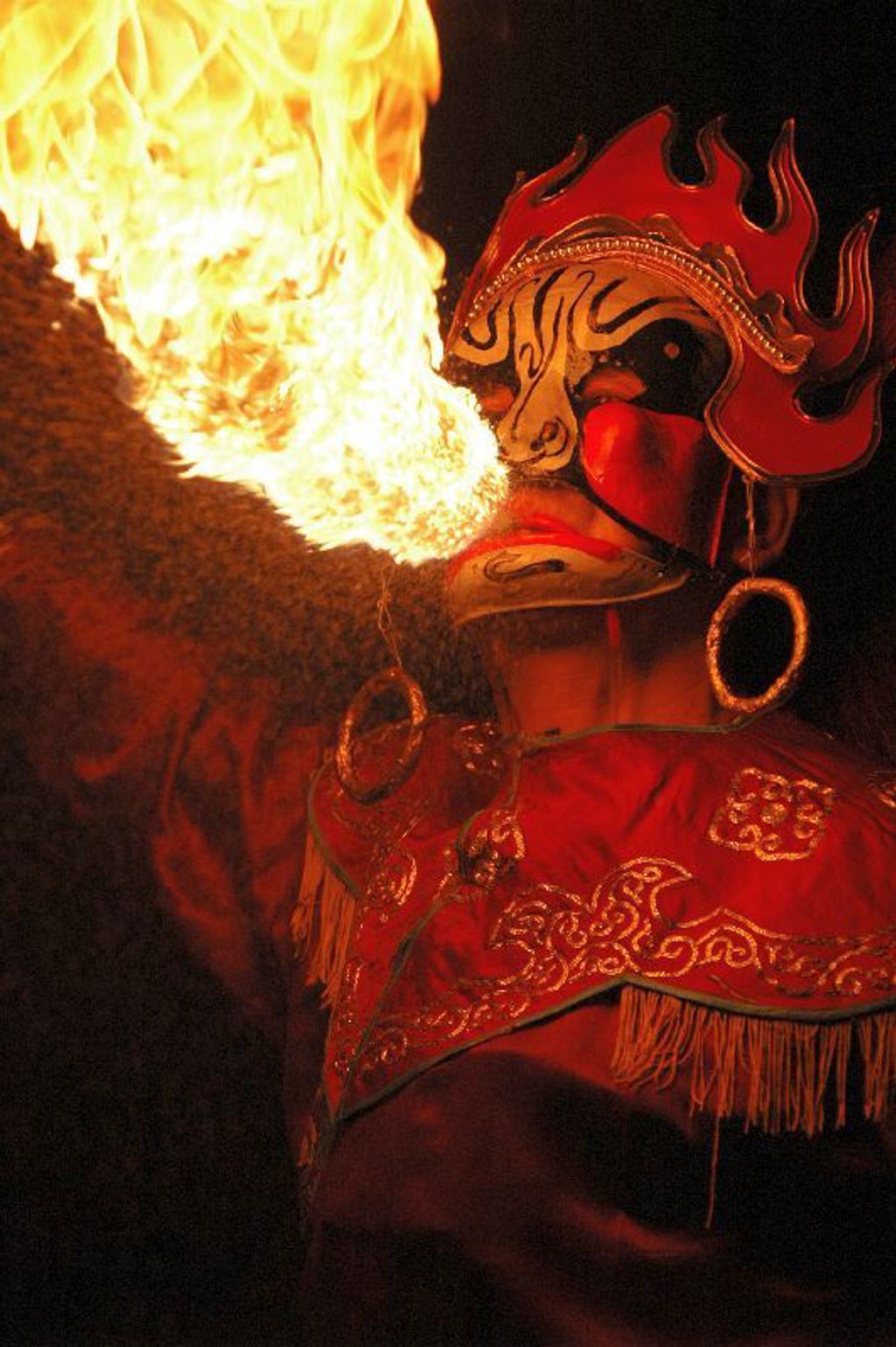 Traditionele Chinese opera-artiest met rood masker blaast vuur tijdens Familiereis China.