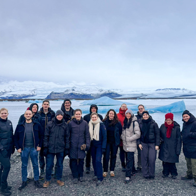 Groep reizigers bij een gletsjermeer met ijsbergen tijdens een winterse groepsrondreis in IJsland.
