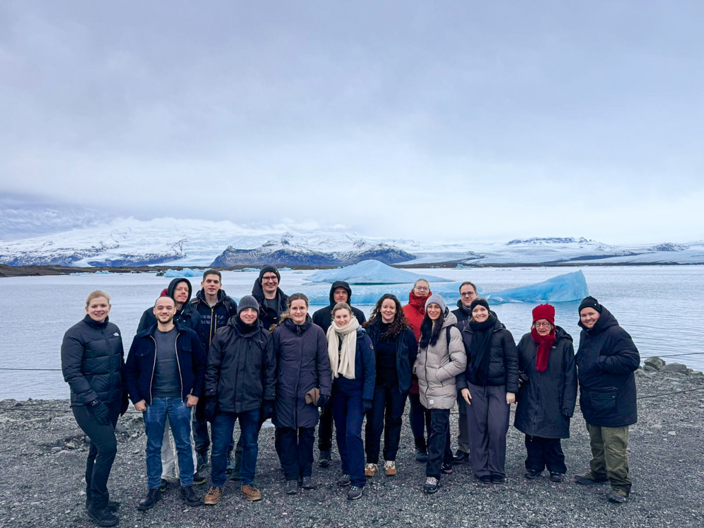 Groep reizigers bij een gletsjermeer met ijsbergen tijdens een winterse groepsrondreis in IJsland.