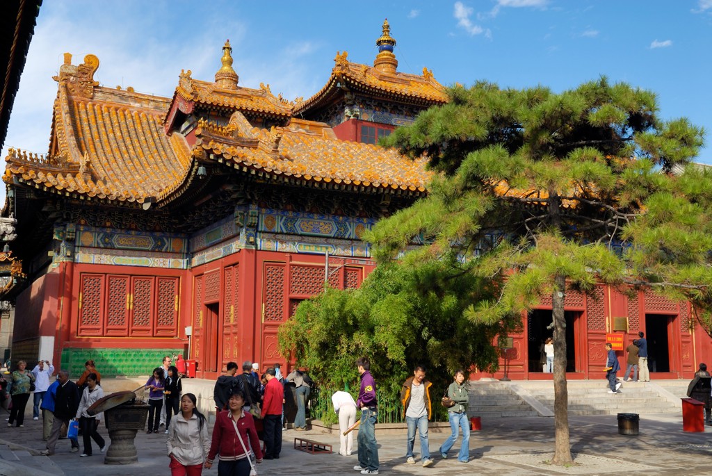 Traditionele Chinese tempel met kleurrijke details en gouden daken, met bezoekers op het plein.