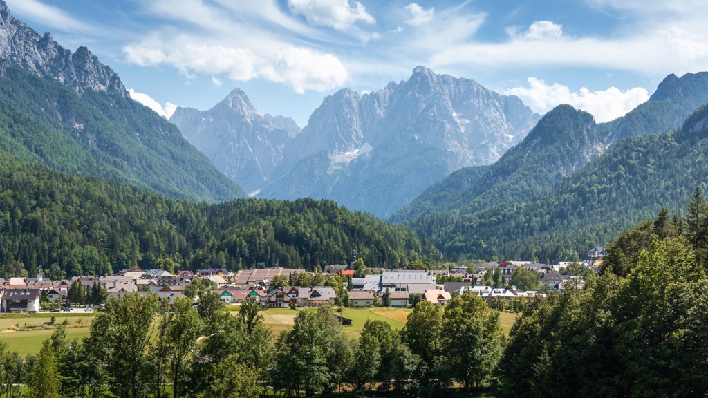 Uitzicht op een Sloveens alpendorp met groene valleien en hoge bergtoppen tijdens een 22-35ers reis Slovenië.