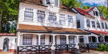 Witte houten gevel van Fort Zeelandia in Paramaribo, met veranda en luiken.