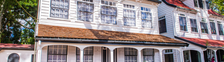 Witte houten gevel van Fort Zeelandia in Paramaribo, met veranda en luiken.