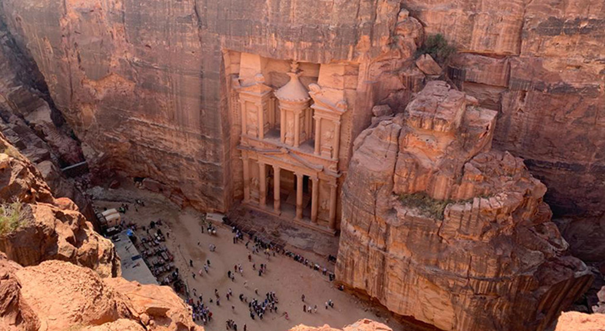 Uitzicht op Al-Khazneh (de Schatkamer) in Petra, uitgehouwen in de rotswand, met bezoekers op het plein.
