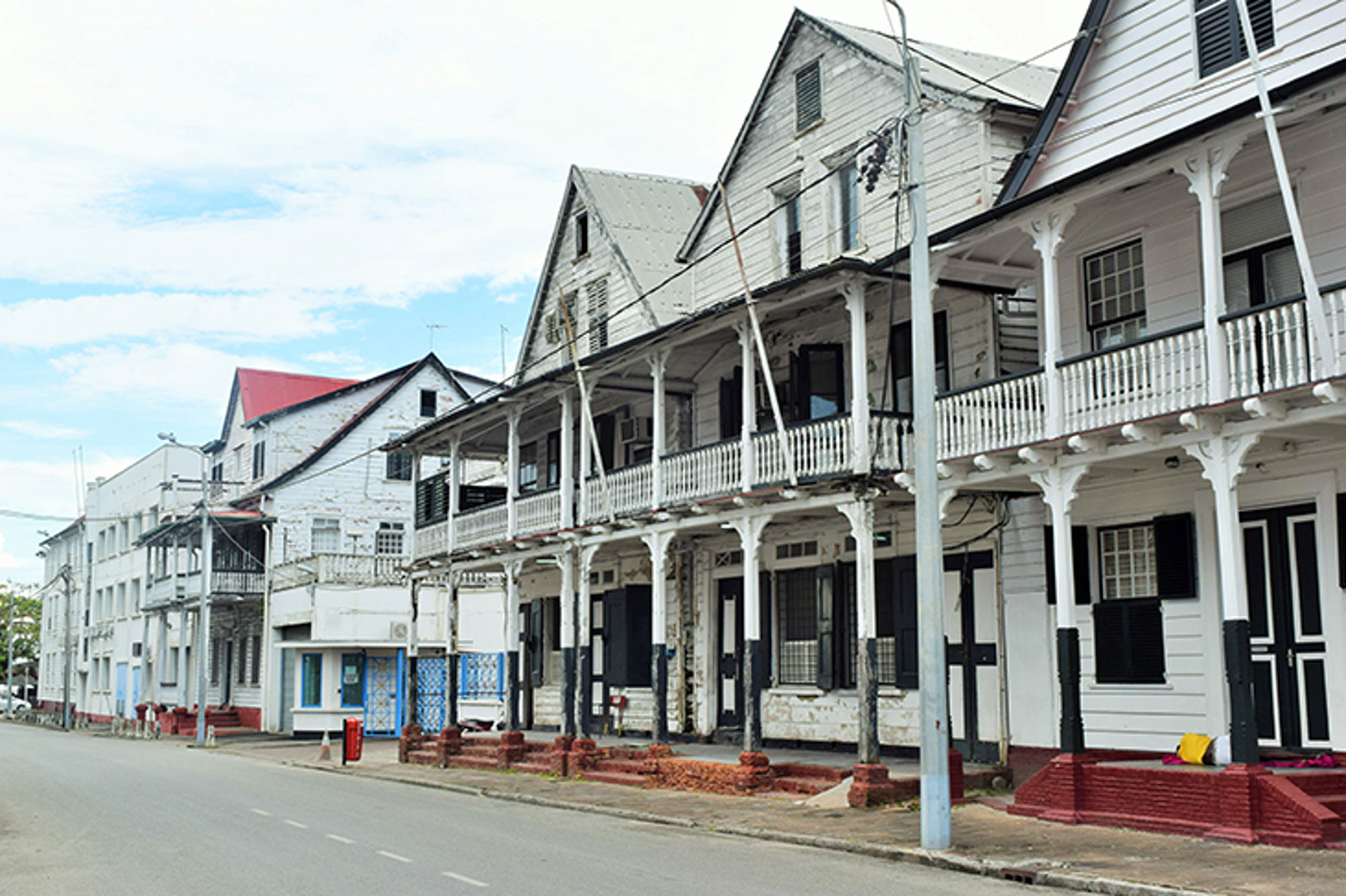 Historische houten koloniale gebouwen met veranda’s langs een rustige straat in Paramaribo, Suriname.