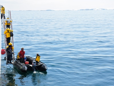 Passagiers stappen vanaf het expeditieschip in een zodiac op zee bij Antarctica.