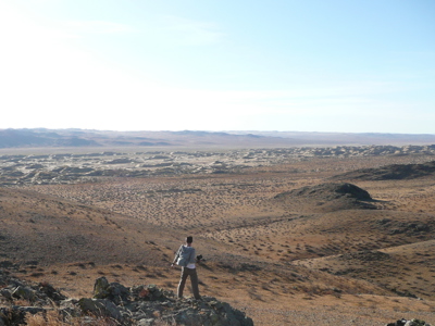 Wandelaar kijkt uit over het uitgestrekte landschap van de Gobiwoestijn in Mongolië.