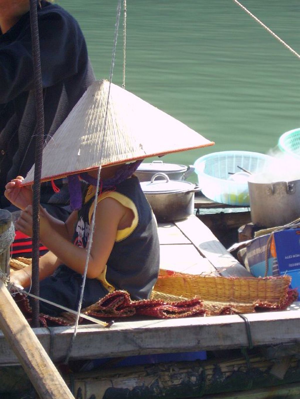 Kind met Vietnamese hoed op een boot op het water tijdens familiereis Vietnam Hoogtepunten.