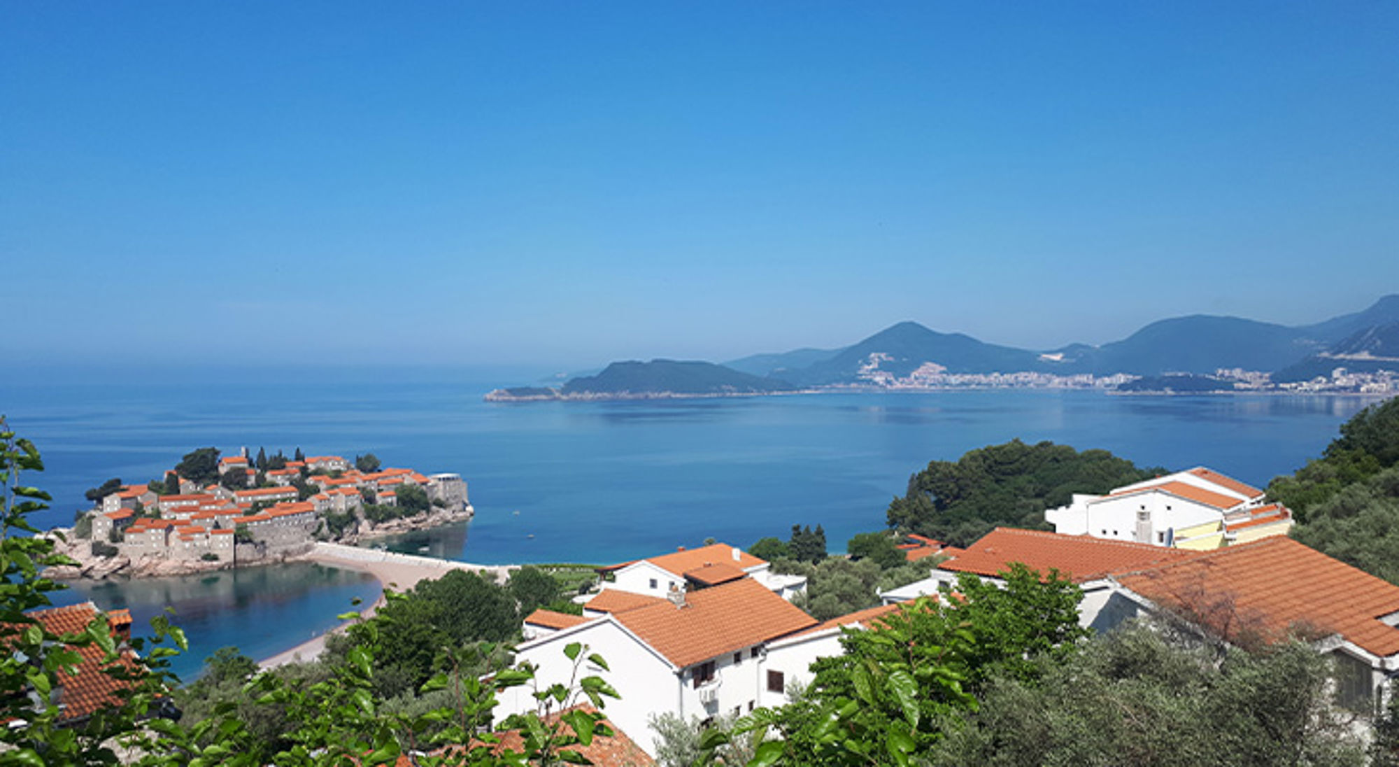 Balkan Uitzicht op Sveti Stefan aan de Adriatische kust in Montenegro, met roodpannen daken en blauwe zee.