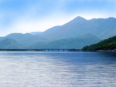 Berglandschap aan het Meer van Skadar met brug en rustige wateroppervlakte tijdens de Route Balkan.
