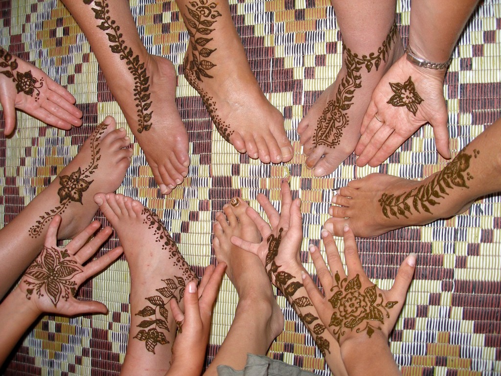 Handen en voeten met henna in een kring op een kleurrijk tapijt tijdens een familiereis Marokko in de zomer.