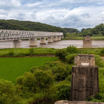Spoorbrug over de Imjin-rivier bij de DMZ in Zuid-Korea, met groene velden en heuvels op de achtergrond.