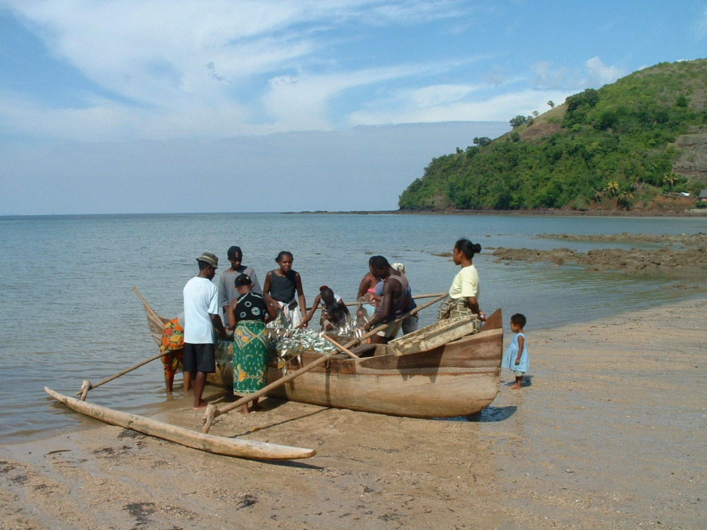 Vissers lossen de vangst uit een traditionele boot op het strand van Madagascar.